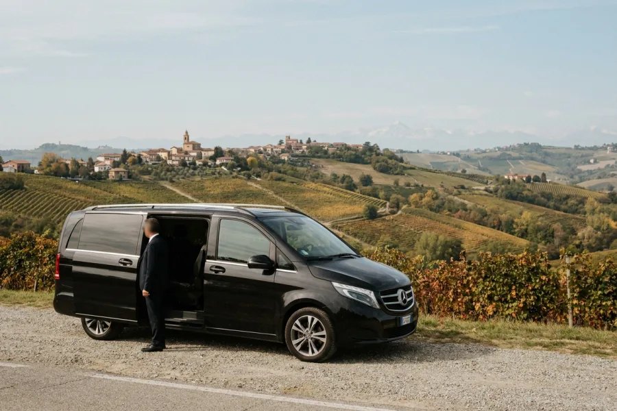 A black minivan parked at a panoramic belvedere over the Langhe